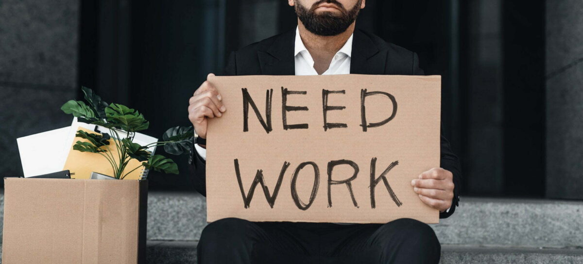 Unemployment after lockdown. Unrecognizable businessman holding cardboard sign with need work text